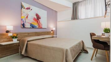 A modern bedroom with a large bed, bedside tables, a desk with a chair, and a window with curtains.