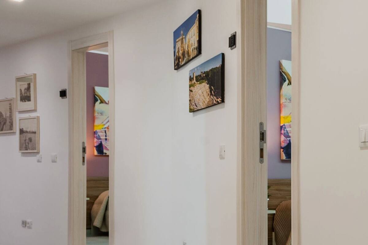 A hallway with white walls, tiled flooring, and several doorways leading to different rooms.
