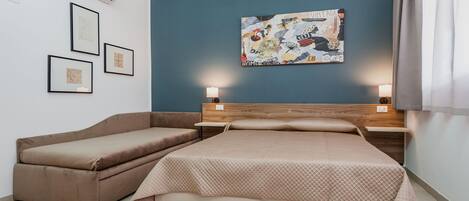 Un dormitorio con cama, sofá cama, aire acondicionado de pared, cuadros enmarcados y una obra de arte en la pared.