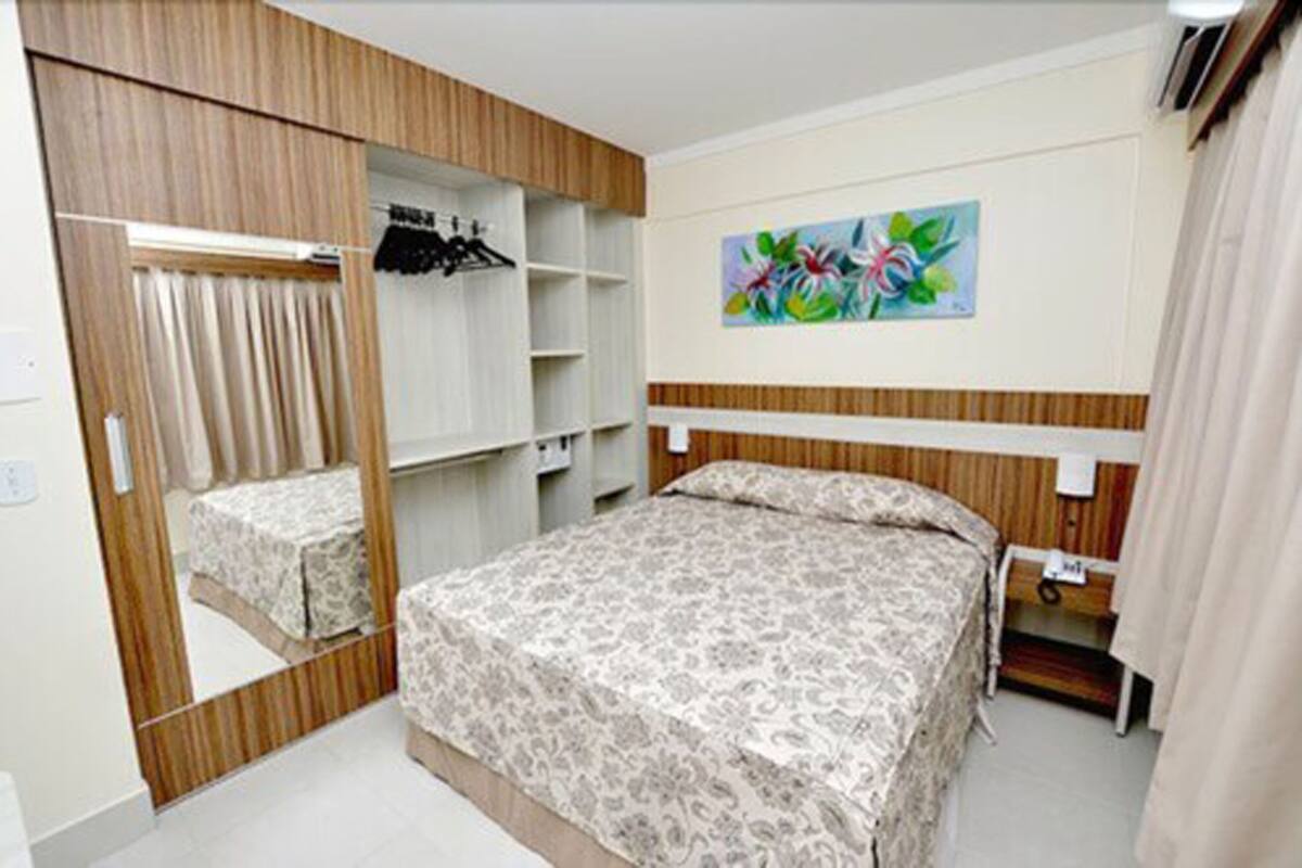 Une chambre à coucher comprenant un lit, une armoire, un miroir, une étagère et un tableau accroché au mur.