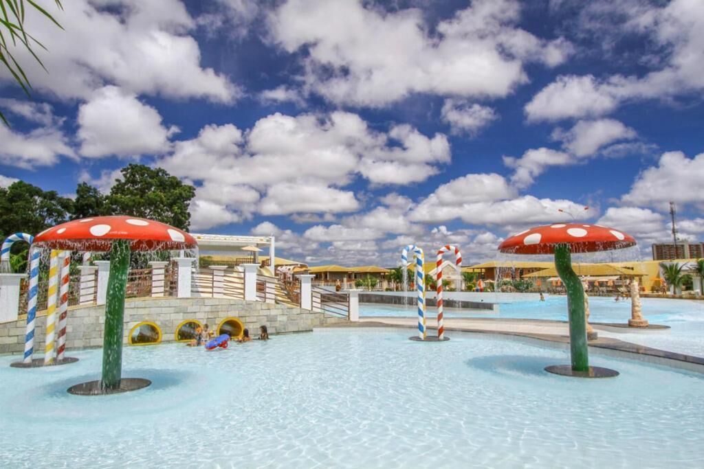 A water park with slides and a pool area, featuring large mushroom-shaped umbrellas and striped poles.
