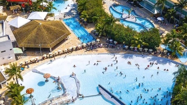 Ein Resort mit mehreren Schwimmbecken, darunter ein großes zentrales Becken, und einem Strandbereich.