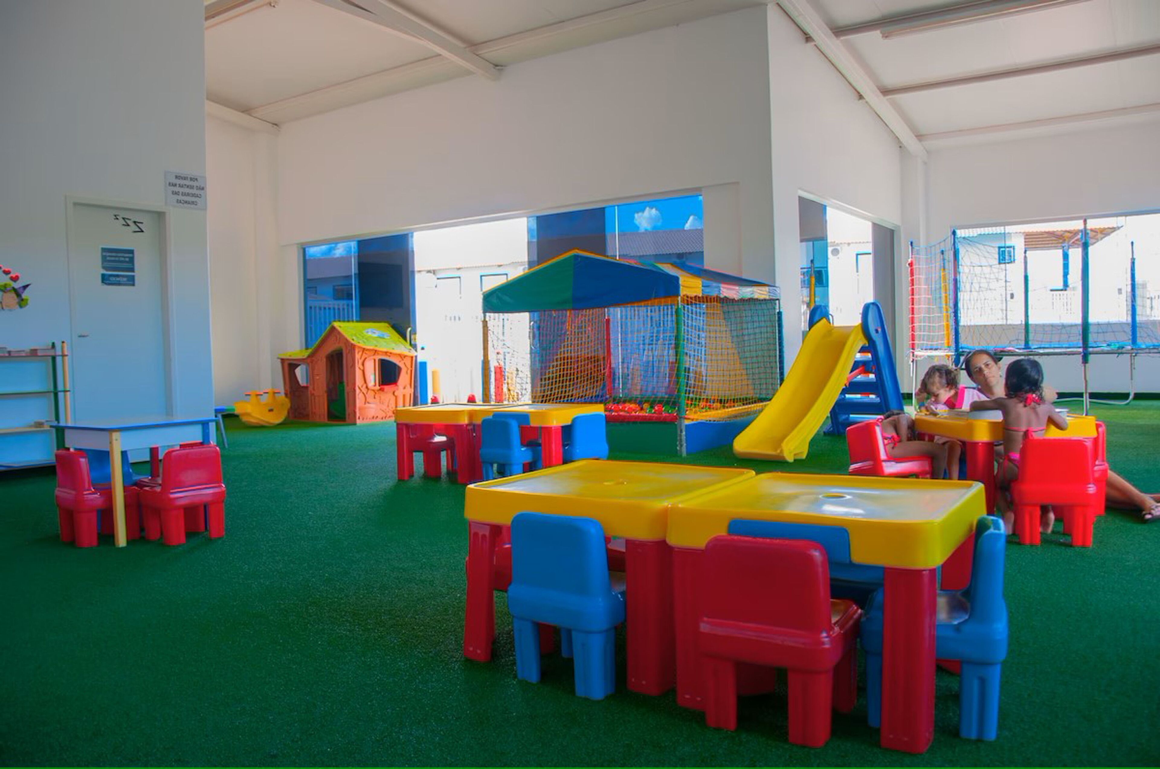 Zona de juegos infantiles con tobogán, estructuras recreativas y mesas y sillas.