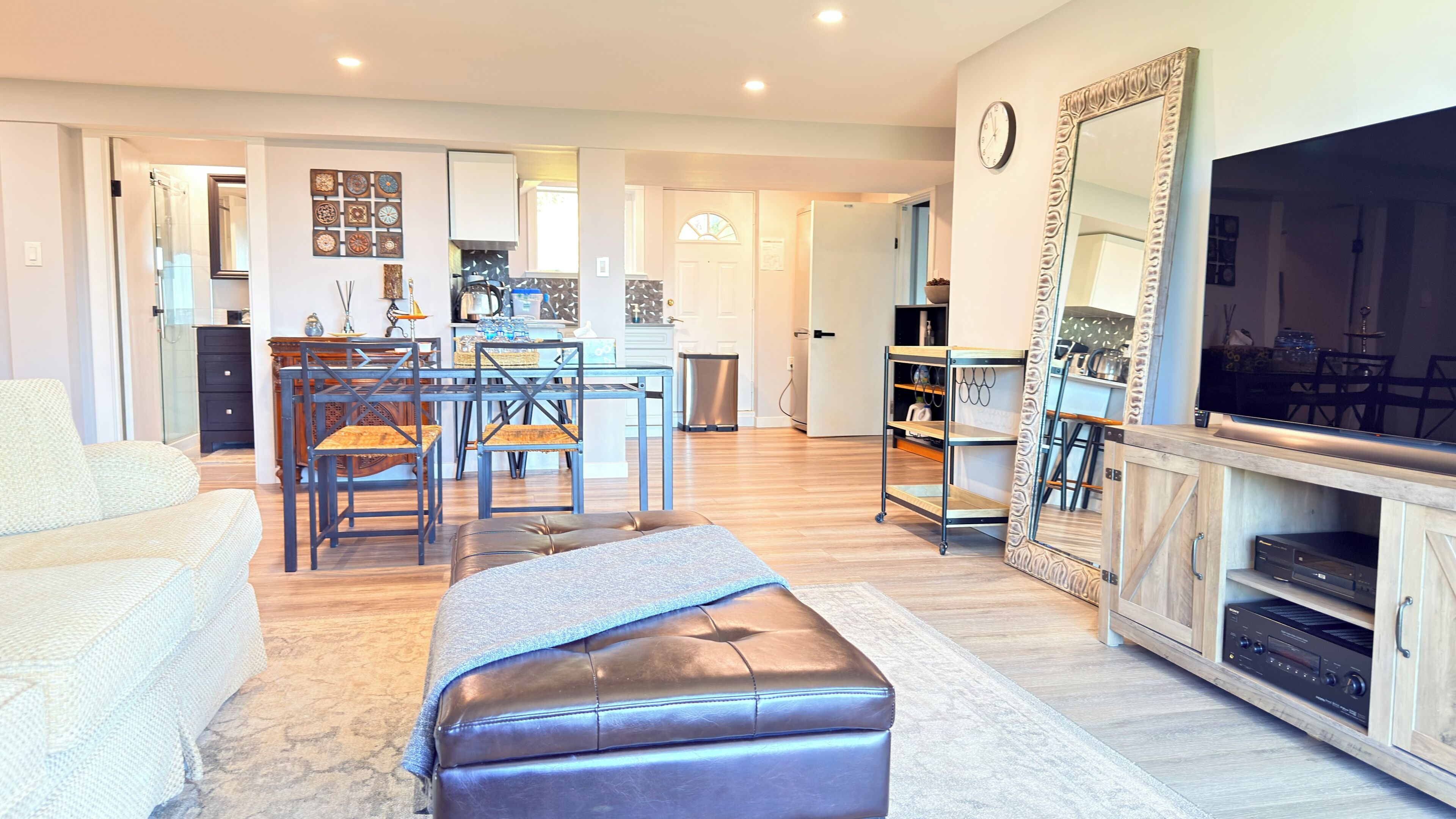 A living room with a sofa, ottoman, and a TV stand with a flat-screen TV and audio system.