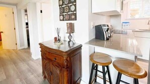 A modern kitchen with white cabinets, a coffee machine, and a decorative clock wall.
