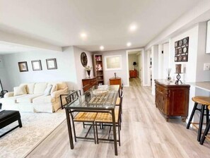 Amplia sala de estar con mesa de comedor de cristal, sofá y mueble de madera.