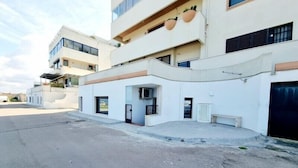 Un immeuble résidentiel moderne à plusieurs étages, doté de balcons, d’une entrée couverte et d’un espace de stationnement.