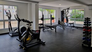 Un gimnasio con equipo cardiovascular, máquinas de pesas y mancuernas.