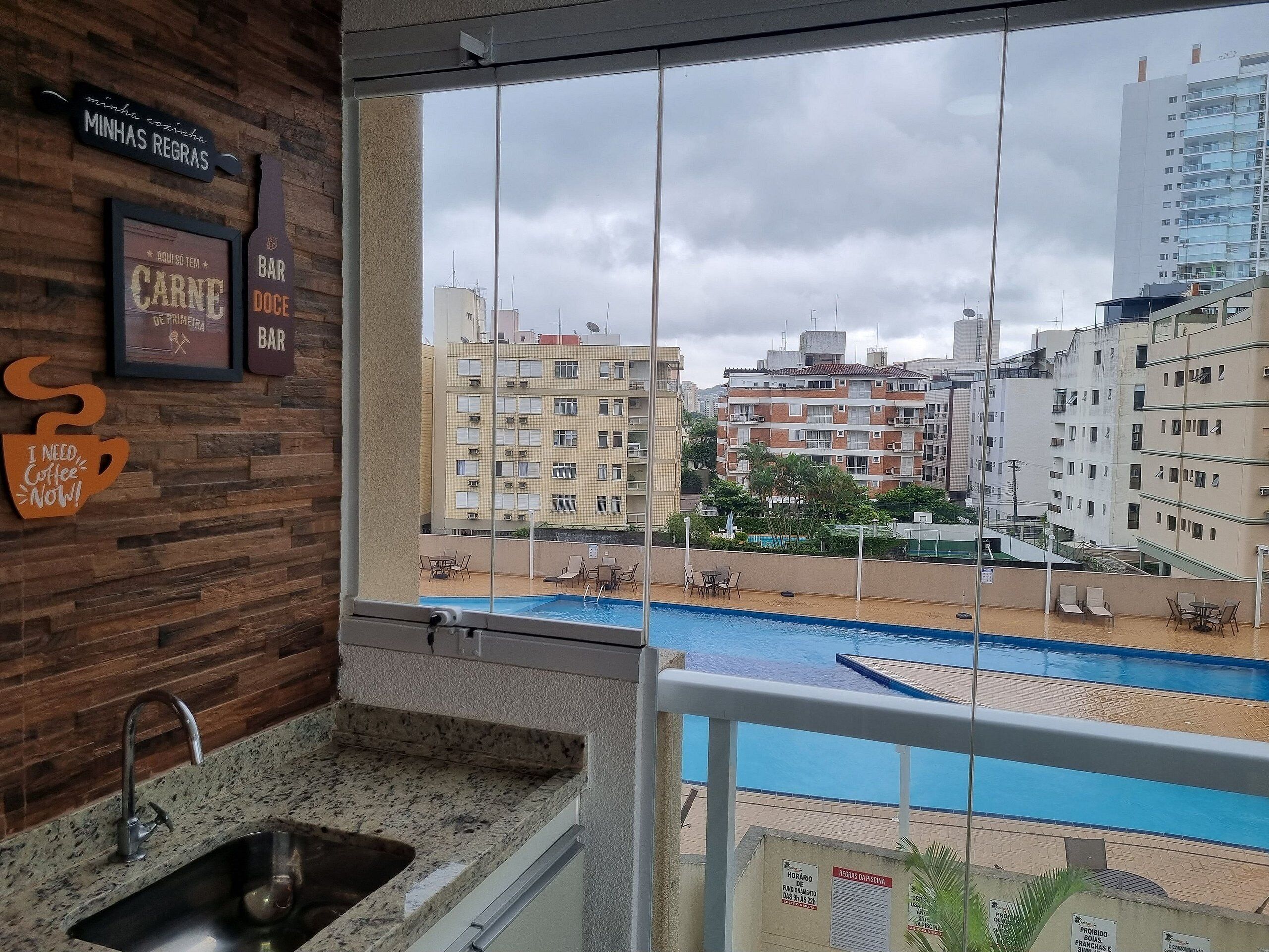 Un balcón con vistas a una piscina y edificios circundantes.