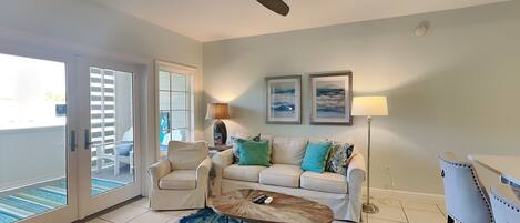 A living room with a ceiling fan, a sofa, a chair, a coffee table, and a floor lamp.