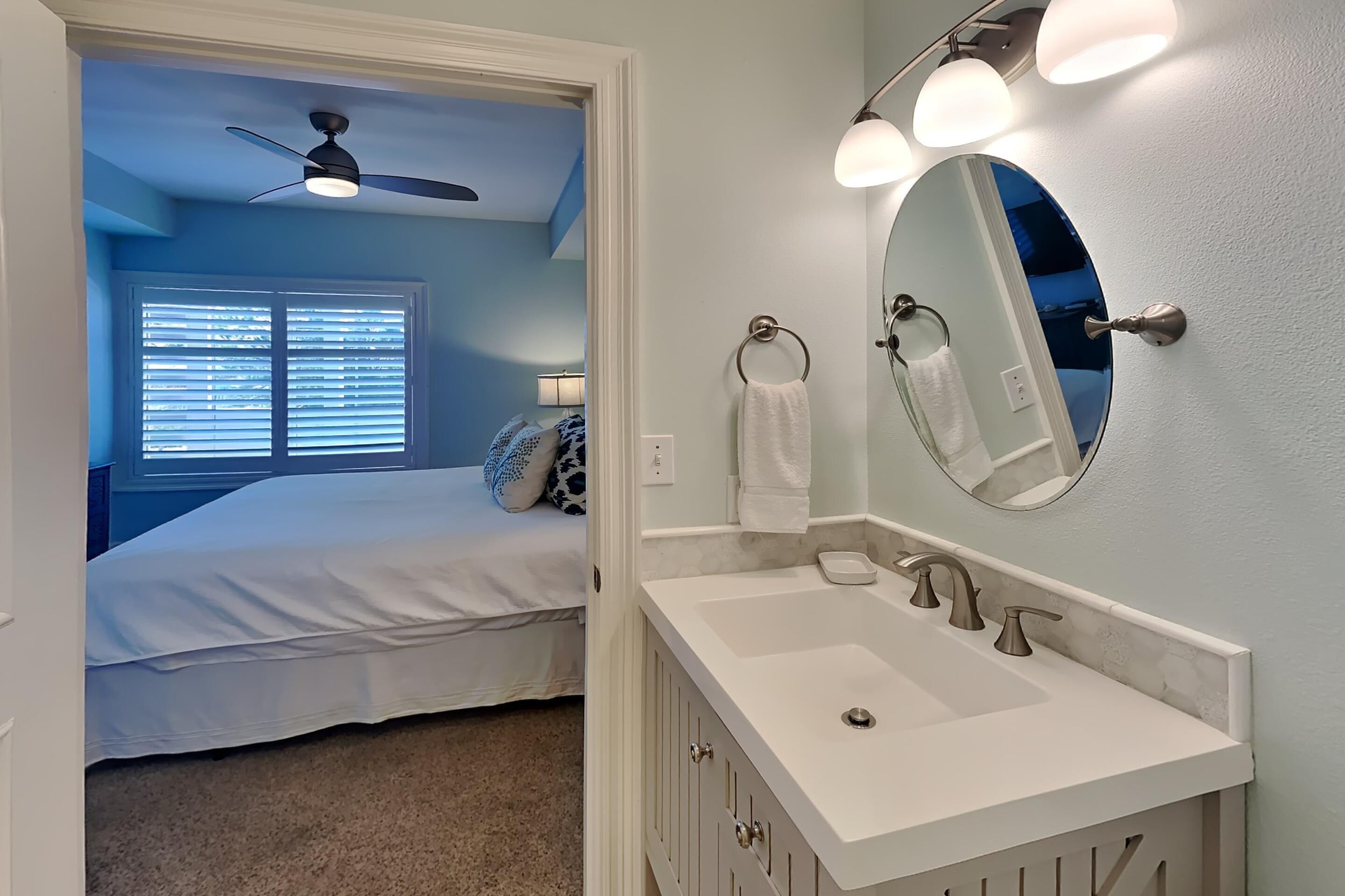 A bedroom with a bed, a ceiling fan, and a window with blinds.