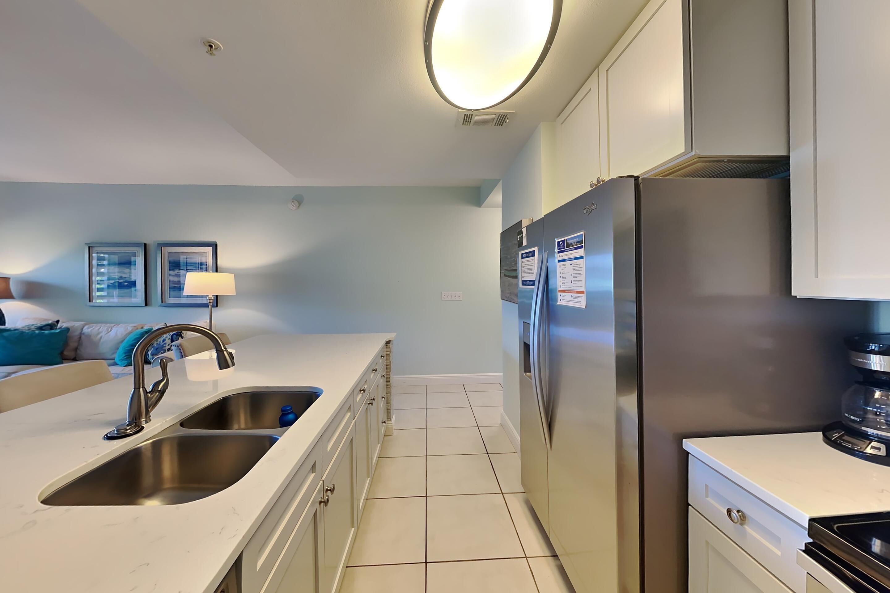 A modern kitchen with stainless steel appliances, a double sink, and a white countertop.