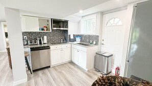A modern kitchen with white cabinets, a stainless steel dishwasher, and a built-in oven. - 2BR Private Suite · West Vancouver · Landmark View · Prime Location (West Vancouver)