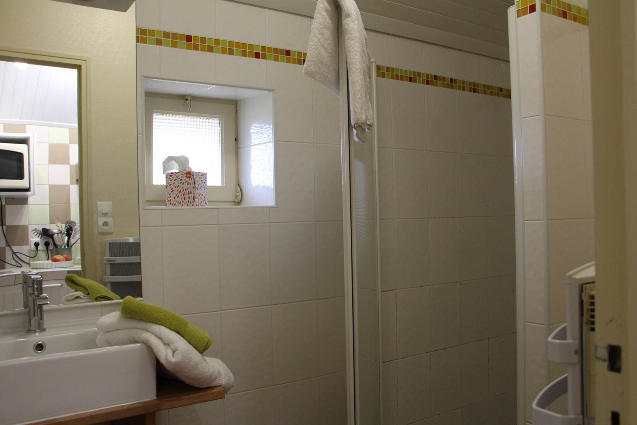 Ein Badezimmer mit Waschbecken, Spiegel und Duschkabine.