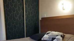 Un letto ben rifatto con copriletto trapuntato e due cuscini, una testata in legno e una parete con decorazioni.