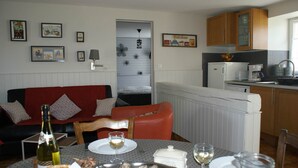 A dining area with a table set for two, a bottle of wine, and a basket of bread. - Cottage Kerruer (CHERRUEIX)