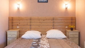 A neatly arranged bedroom with a wooden headboard, two bedside tables with lamps, and a patterned bedspread. - Cottage Roazhon (CHERRUEIX)