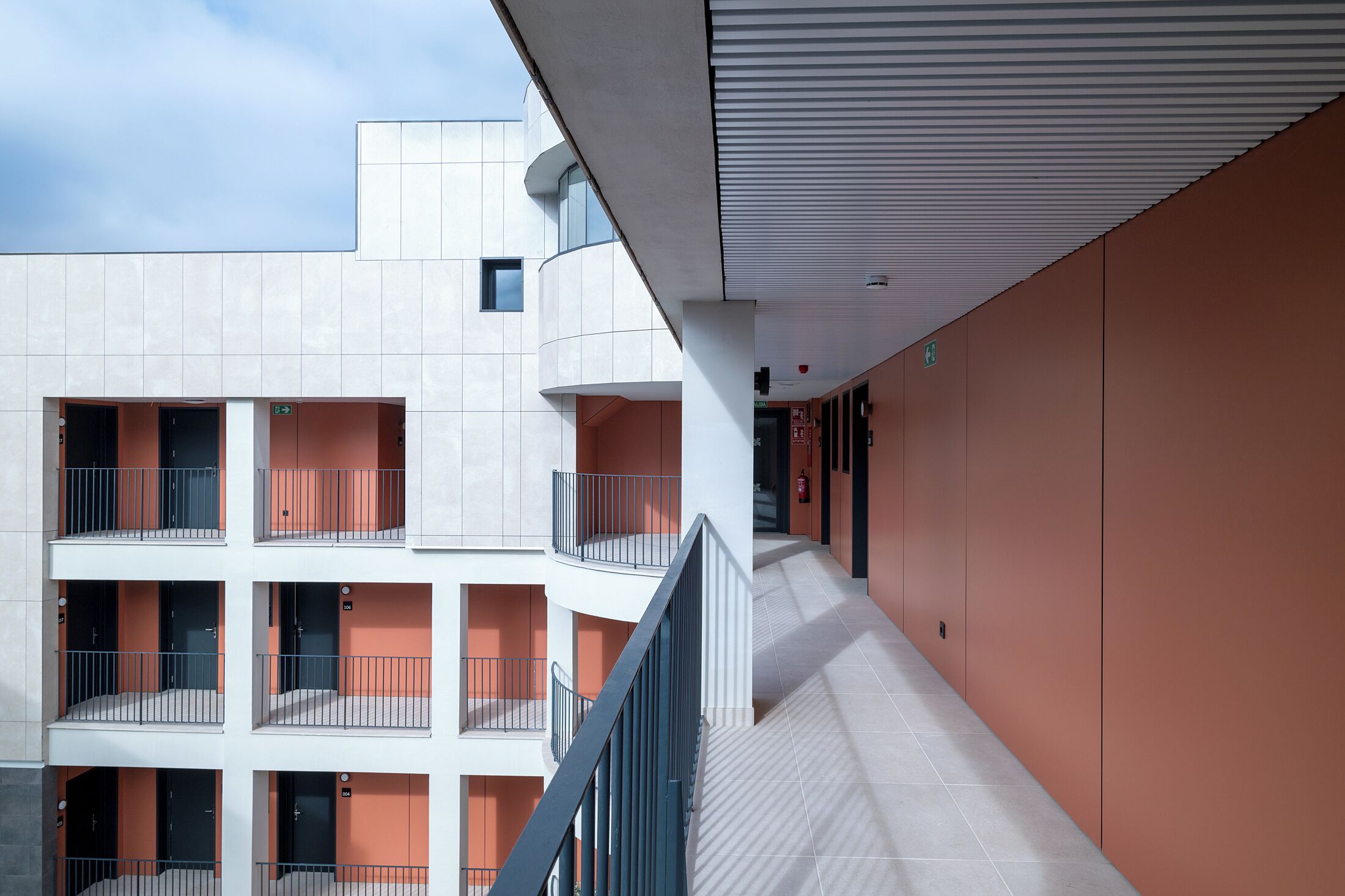 Un edificio de varios niveles con balcones, una escalera y un pasillo.