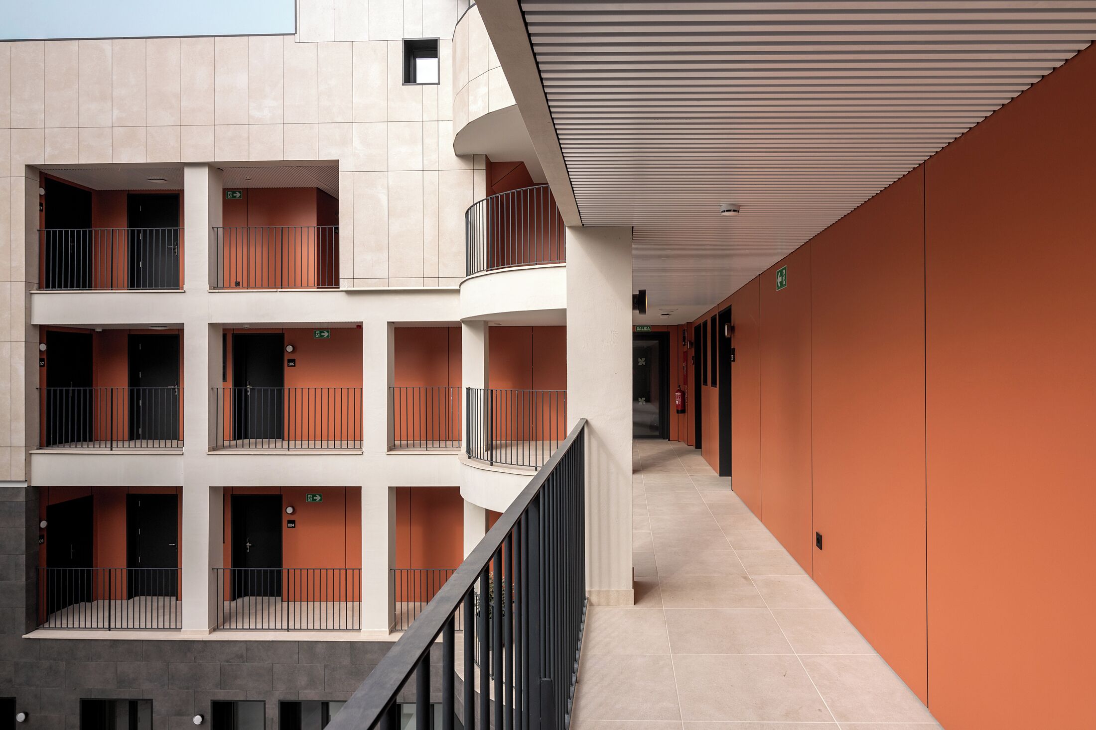 Un immeuble à plusieurs étages doté de balcons, d’un sol carrelé et de murs orange.