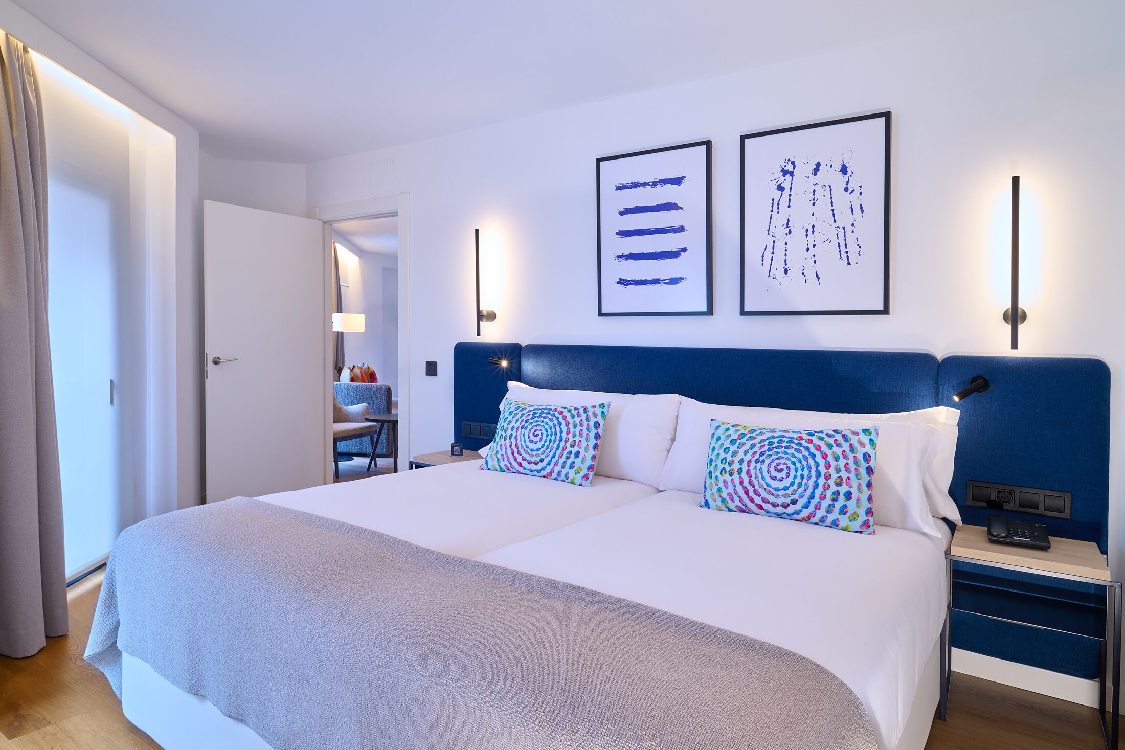 A double bed with a blue headboard, two side tables, and a bedside lamp.