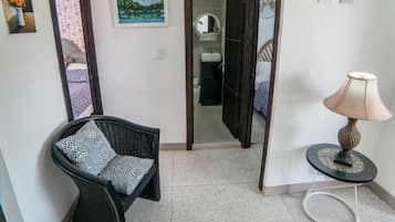 Un pasillo con una silla, una lámpara y un cuadro en la pared.