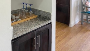 A kitchen with dark wooden cabinets, granite countertops, and a blue bowl on the upper shelf. - Apartamentos Magallanes Romana (La Romana)
