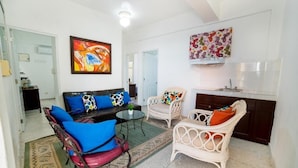 A modern living room with a sofa, chairs, a coffee table, and artwork on the walls. - Apartamentos Magallanes Romana (La Romana)