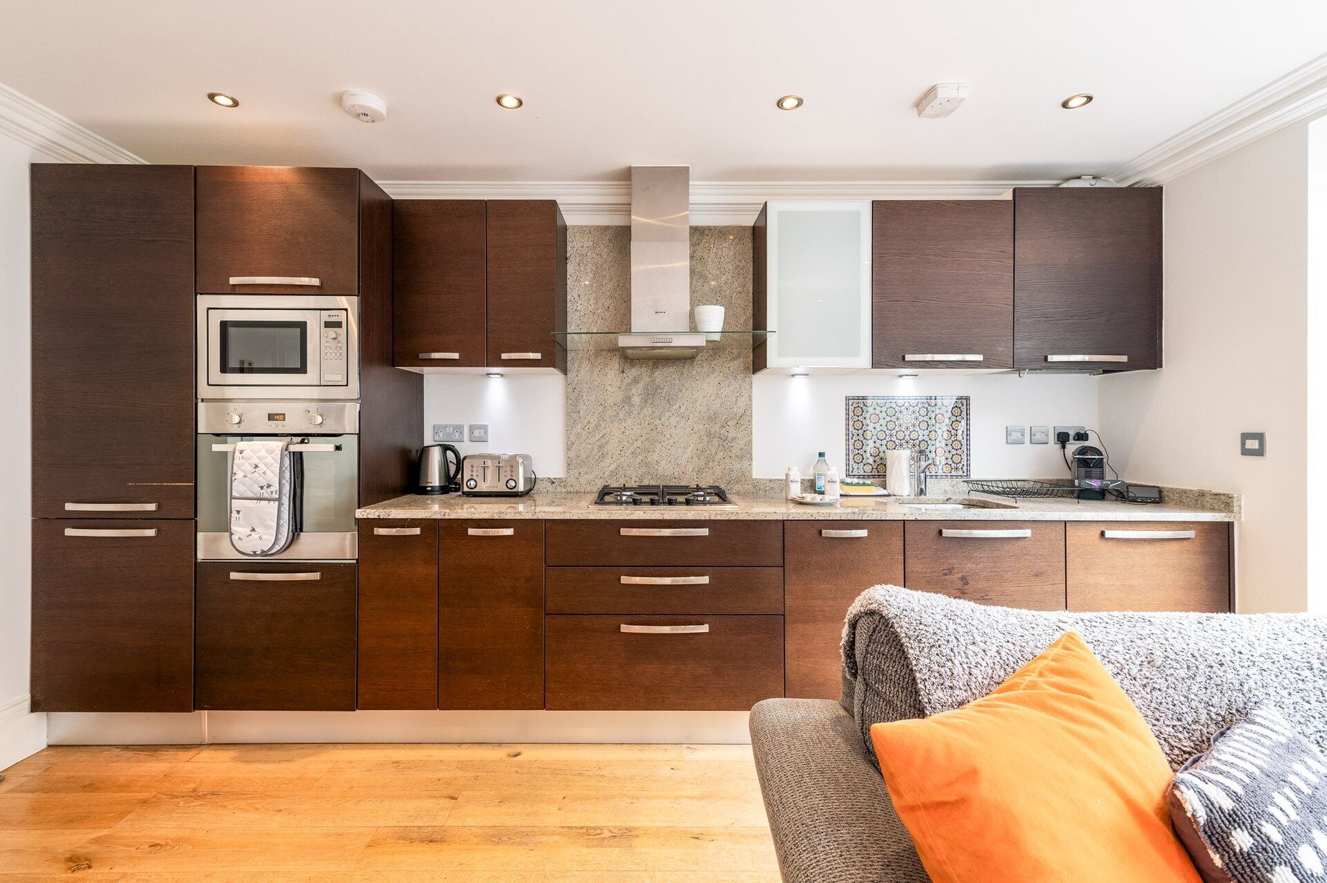 A modern kitchen with dark wood cabinets, stainless steel appliances, and a granite countertop.