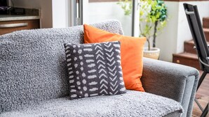 A grey sofa with a patterned pillow and an orange pillow. - Gorgeous Kentish Town Flat (London)