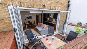 A patio with a wooden table, chairs, and a sofa. - Gorgeous Kentish Town Flat (London)
