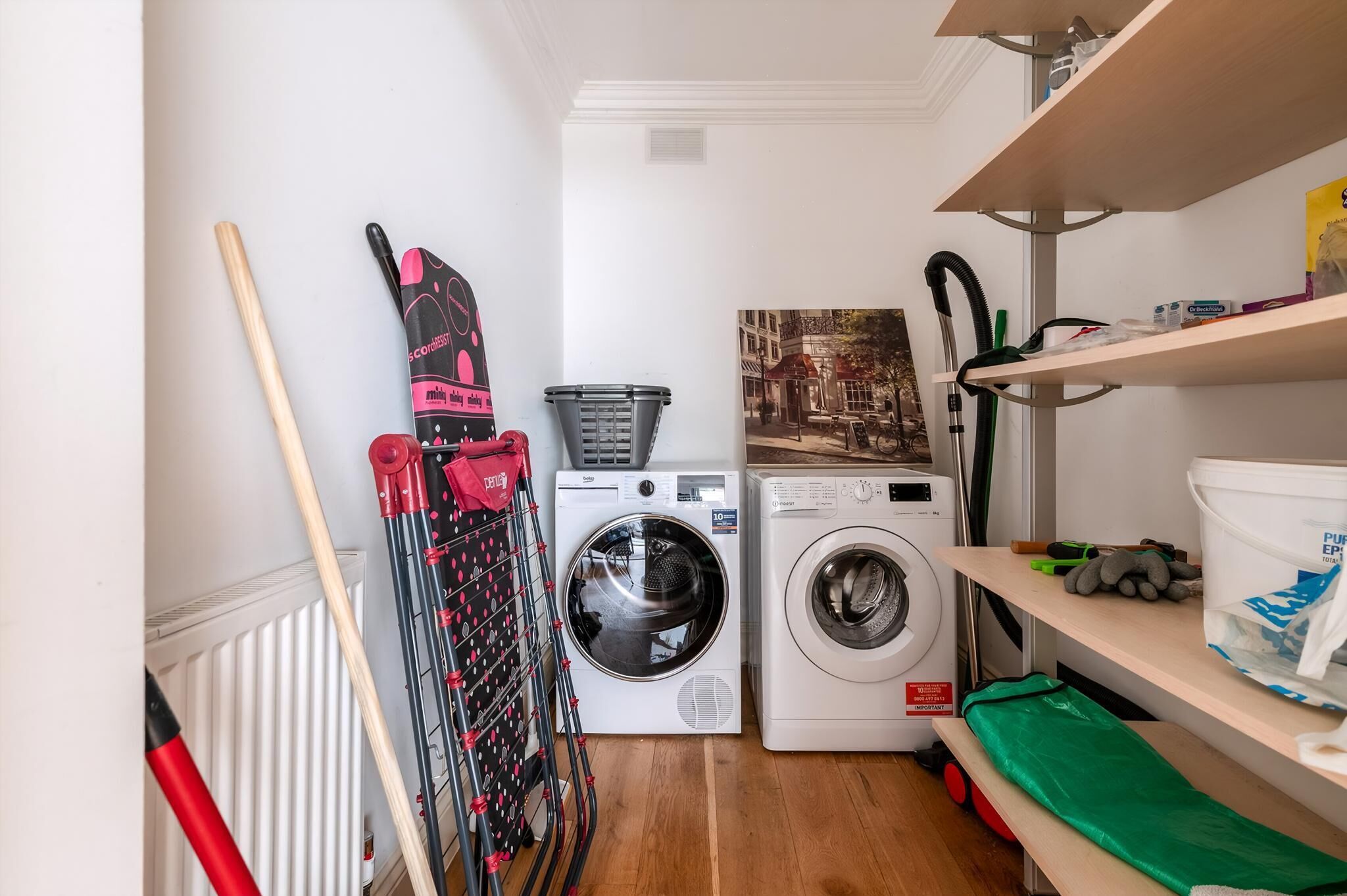 Un espace buanderie comprenant un lave-linge, un étendoir et un radiateur.