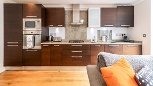 A modern kitchen with dark wooden cabinets, stainless steel appliances, and a built-in oven. - Gorgeous Kentish Town Flat (London)