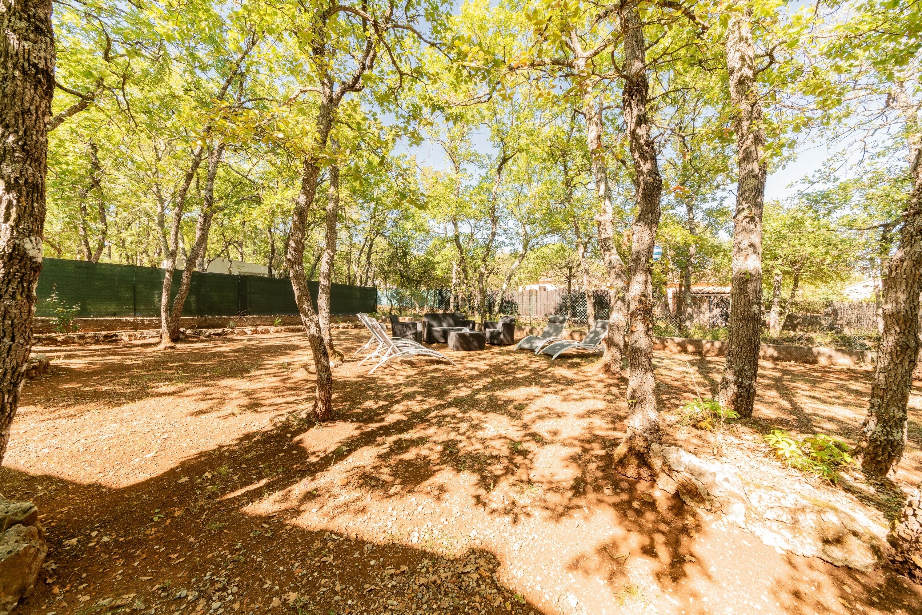 Spazio all'aperto con alberi, una zona relax e un'area recintata.