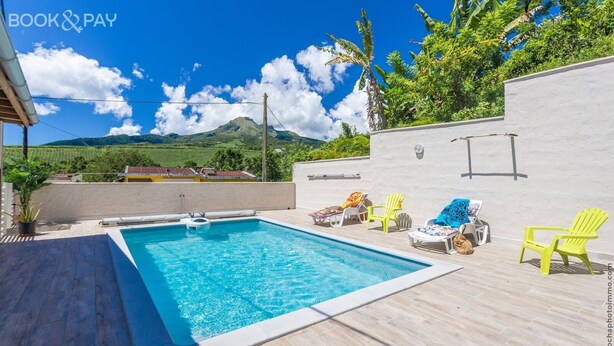 Une piscine avec vue sur les montagnes et un mur blanc.