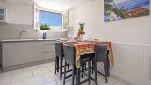 Une cuisine avec un coin repas, une fenêtre donnant sur un beau paysage et un tableau accroché au mur.