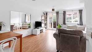 A modern living room with a sofa, TV, and a dining area with a table and chairs. - Beautiful Three-bedroom House in Richmond (Richmond)