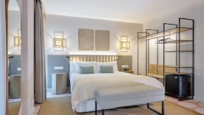 Una habitación de hotel moderna con una cama grande, mesitas de noche, un armario y un espejo.