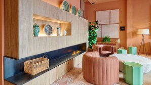 Una habitación de hotel moderna con una pared de acento de madera, chimenea, sofá, cama y una pequeña mesa con una planta.