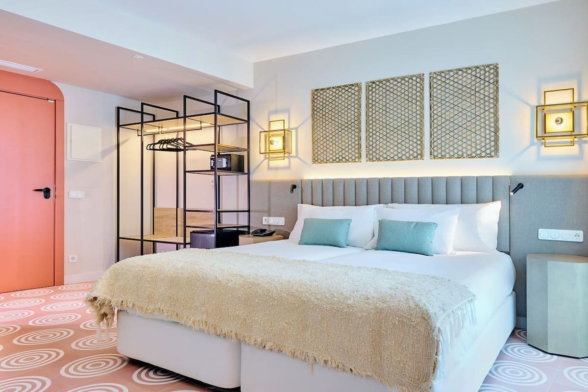A modern hotel room with a large bed, a walk-in closet, and decorative wall panels.