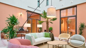 Un espacio interior moderno con un sofá, sillas, una mesa y plantas en macetas.
