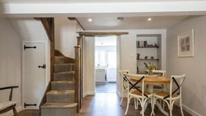 A staircase leading to a dining area with a table and chairs. - Cosy cottage in a pretty village with a pub at the end of the garden! (Buckland Newton)