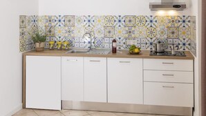 A kitchen with white cabinets, a stainless steel sink, and a backsplash with a geometric tile pattern. - La Natura x9 (Sorrento)