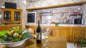 A kitchen with wooden cabinets, a built-in oven, a microwave, and a sink. There is a bowl of fruit on the counter and a wine bottle. - La Natura x9 (Sorrento)