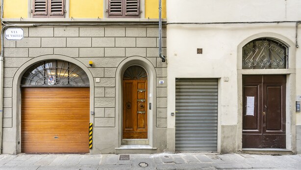 Vista de la calle de un edificio con tres puertas: una de madera, un cerrojo metálico y una marrón con un ventanal decorativo.