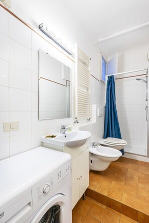 Un bagno moderno dotato di lavatrice, lavabo, wc e doccia.