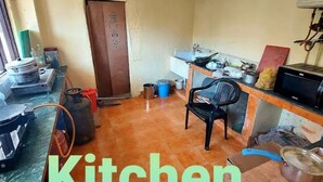 A compact kitchen with basic amenities, a door, and a counter with various items. - Cozy Mountain-View Room near Mcleodganj in Dharamshala Homestay (Dharamshala)