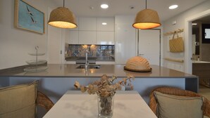 A modern kitchen with white cabinets, a central island, and a hanging light fixture. - Los Flamencos 4004 - Two Bedroom Apartment, Sleeps 5 (Punta del moral)