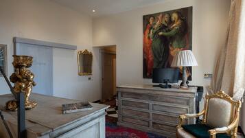 A room with a desk, a chair, a large painting, a lamp, and a patterned carpet.
