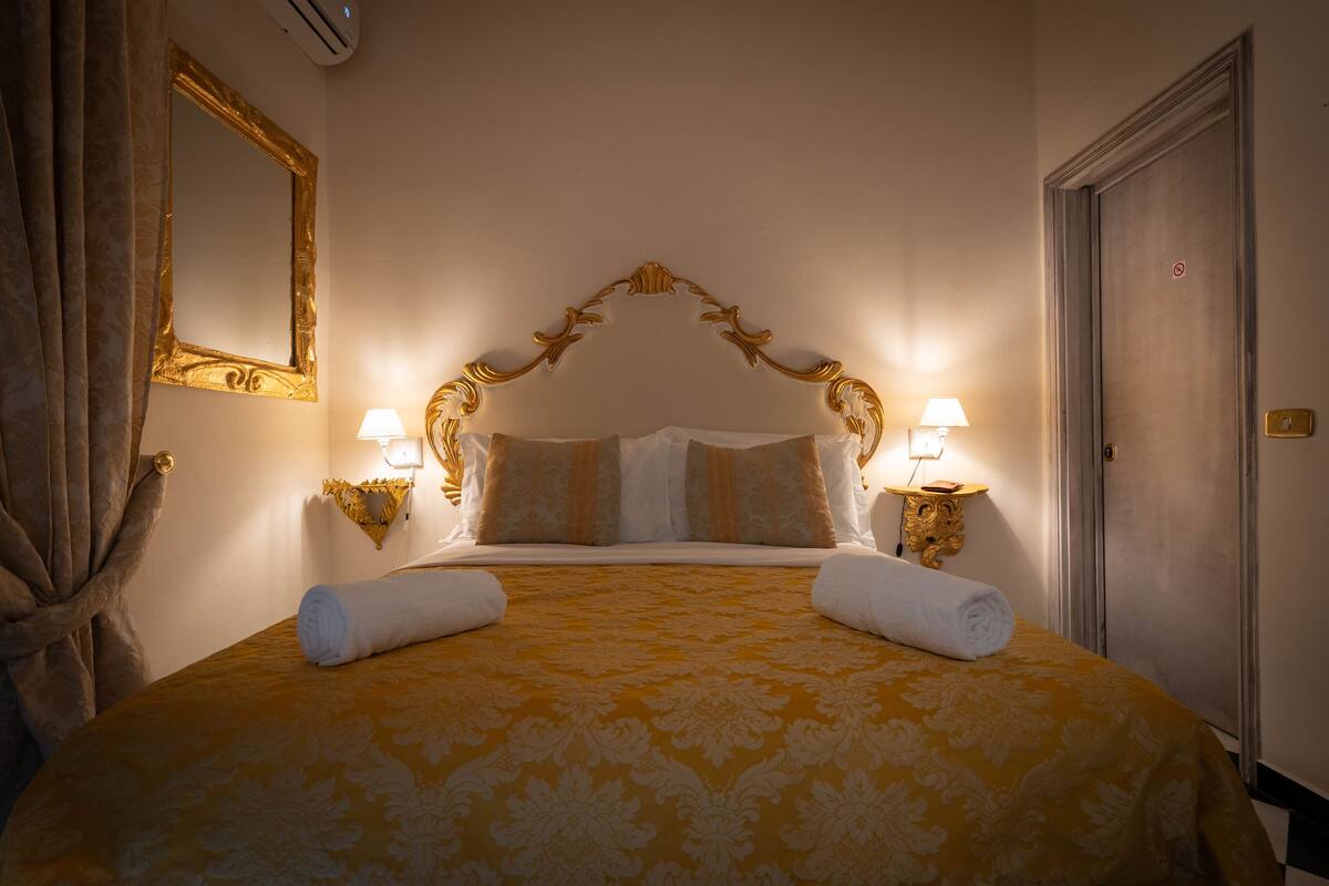 A hotel room with a large bed, two bedside lamps, a mirror, and a door.