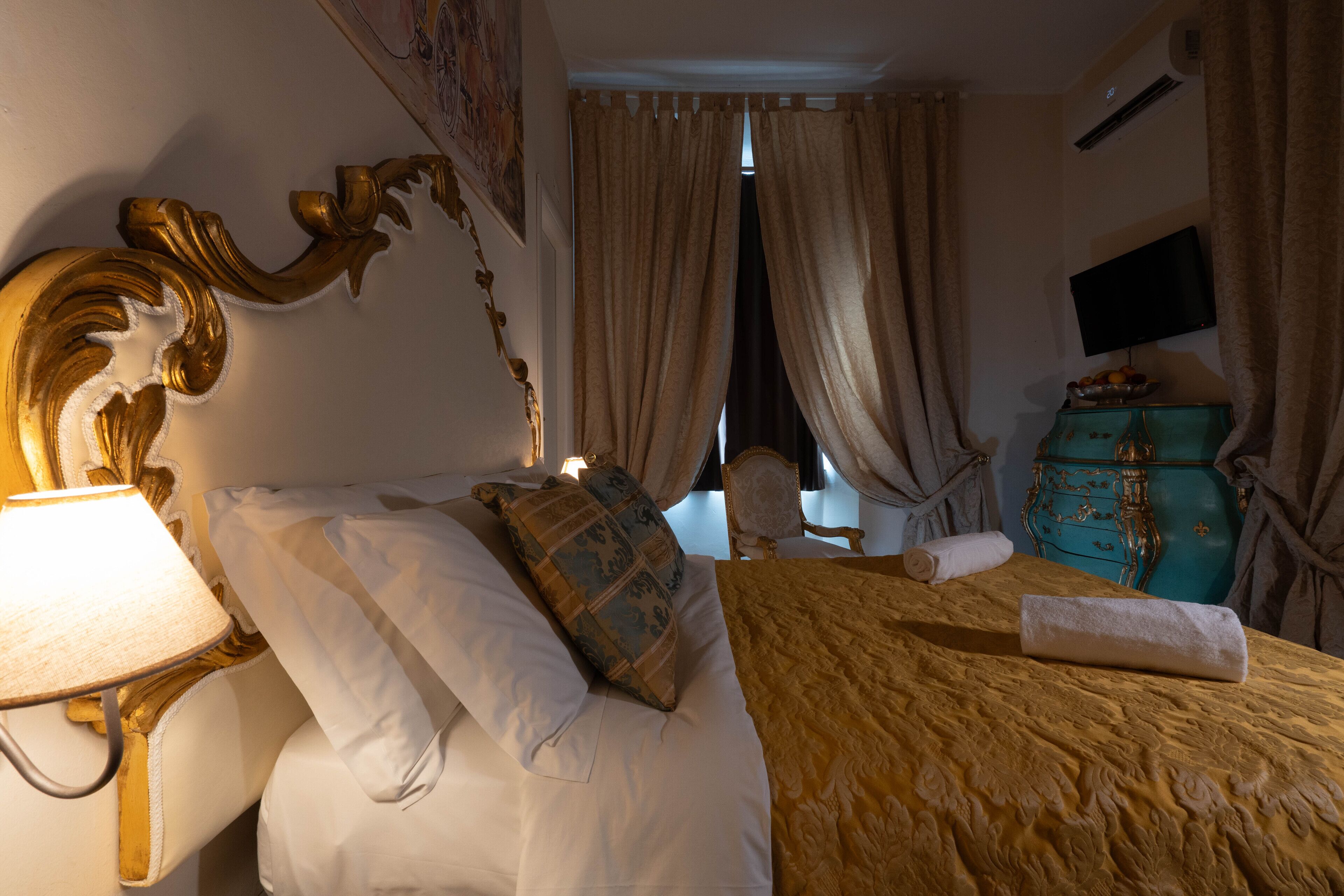 Een hotelkamer met een bed, een lamp, een televisietoestel en een dressoir.